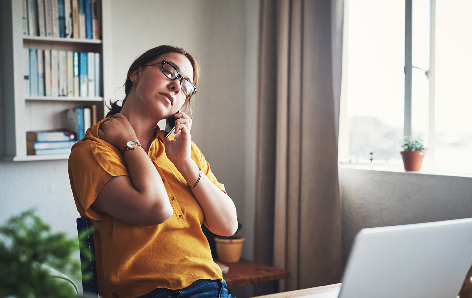 Woman holding neck on phone