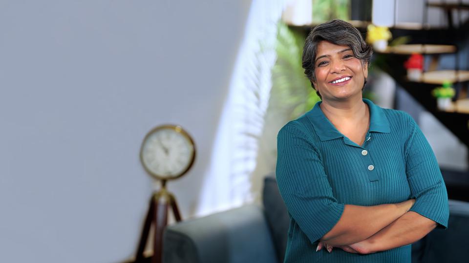 Joyce smiling in a blue shirt with her arms crossed.